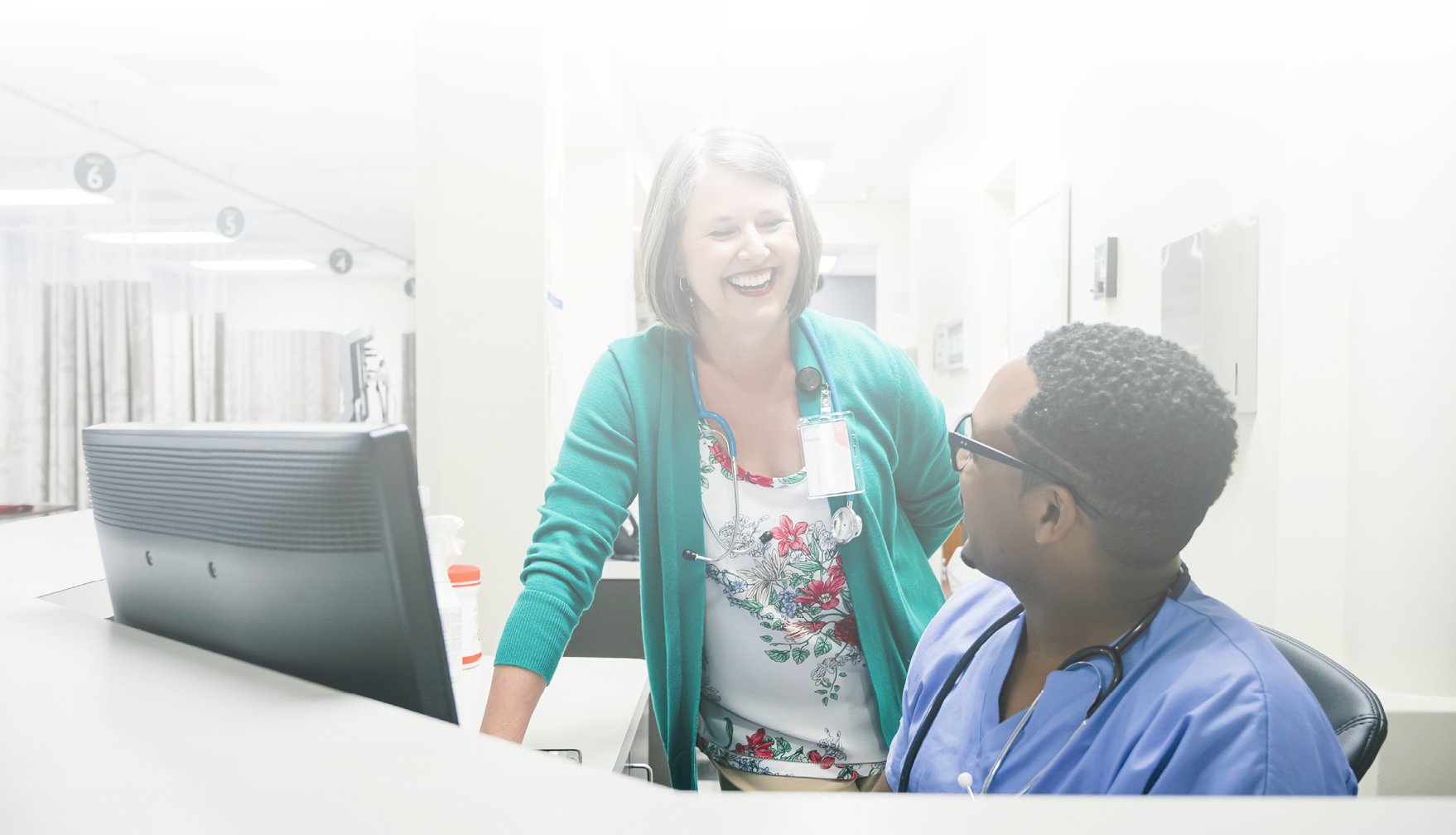 Doctor and nurse laughing near computer